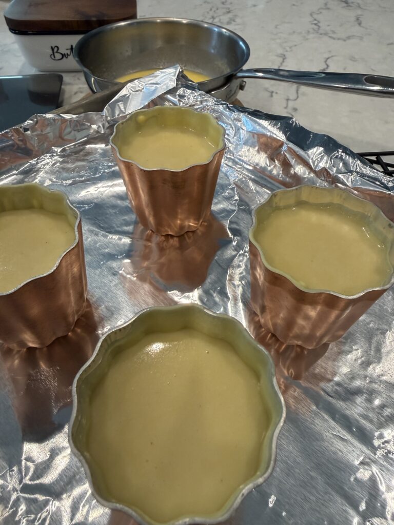 Canelé batter resting in traditional copper molds