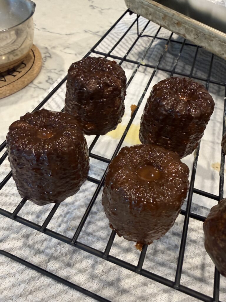 Freshly baked French canelés cooling on a rack